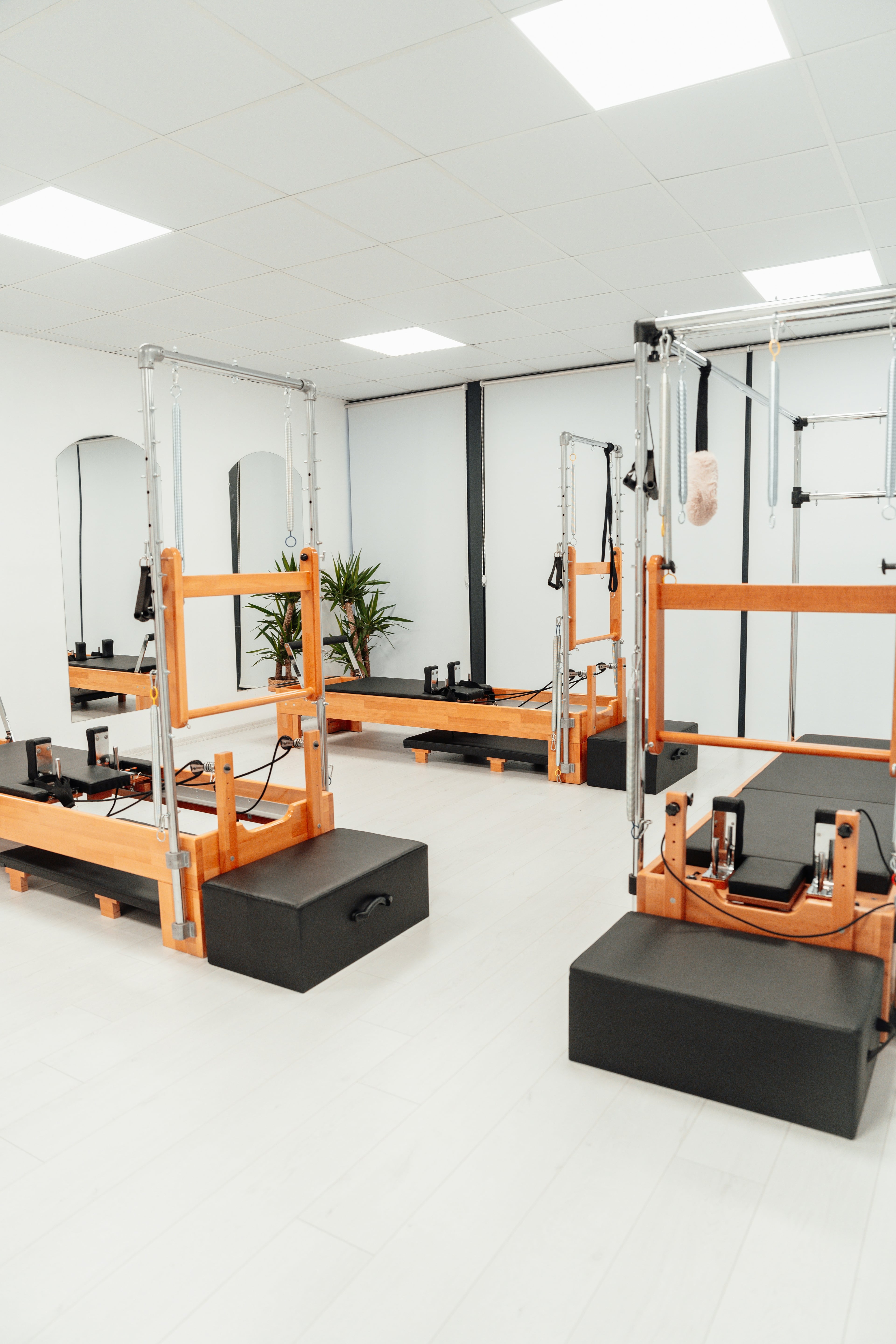 Sala principal de Pilates com reformers modernos e iluminação natural abundante